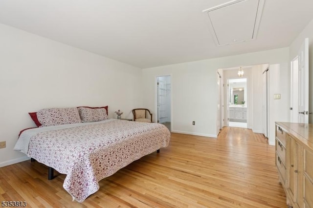 bedroom with light wood-style floors, attic access, and baseboards