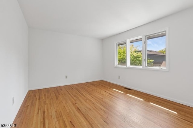 empty room featuring baseboards, visible vents, and light wood-style floors