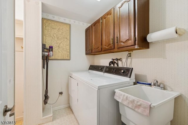 washroom with washer and dryer, baseboards, wallpapered walls, a sink, and cabinet space