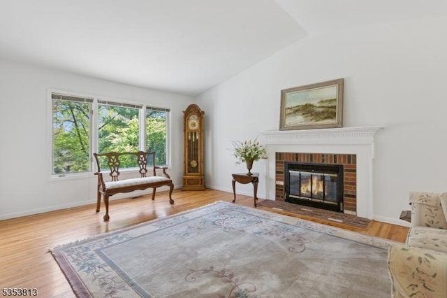 sitting room featuring baseboards, vaulted ceiling, wood finished floors, and a fireplace
