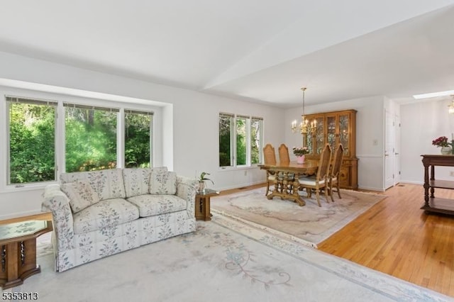 living room with an inviting chandelier, baseboards, and wood finished floors