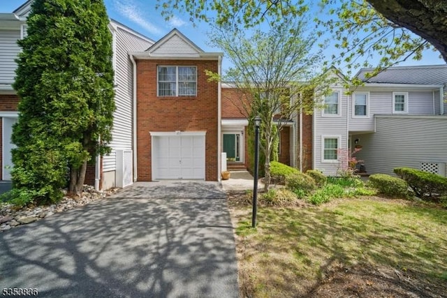view of property featuring an attached garage, driveway, and brick siding