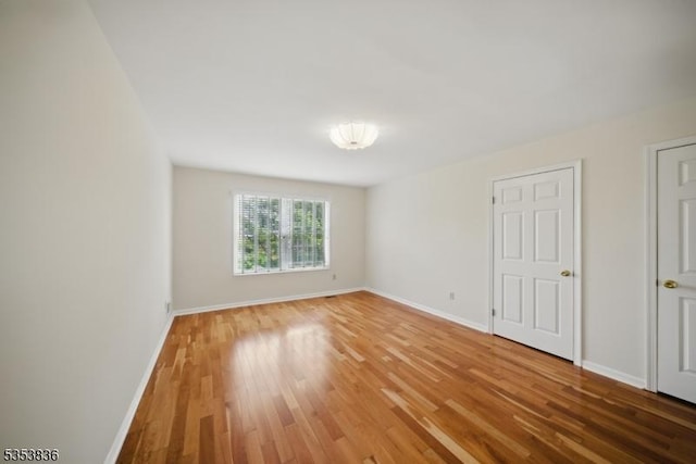 spare room with light wood-style floors and baseboards