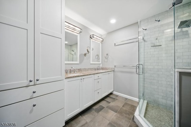 full bath featuring a sink, double vanity, recessed lighting, baseboards, and a shower stall