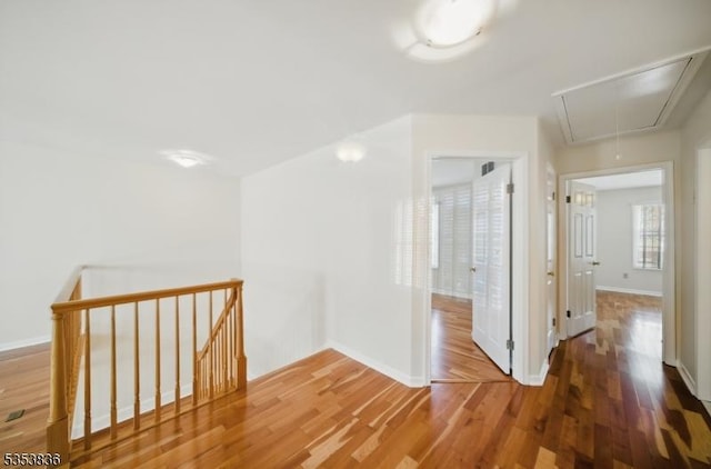 additional living space featuring baseboards, wood finished floors, and attic access