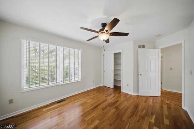 unfurnished bedroom with visible vents, wood finished floors, and multiple windows