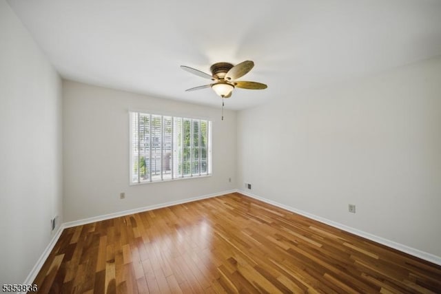 unfurnished room with baseboards, ceiling fan, wood finished floors, and visible vents