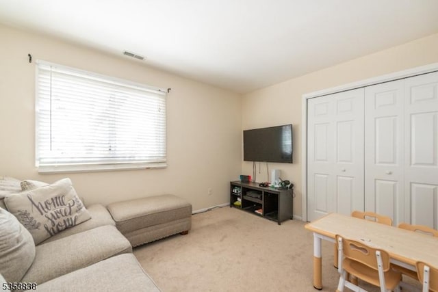 living area with visible vents and light carpet