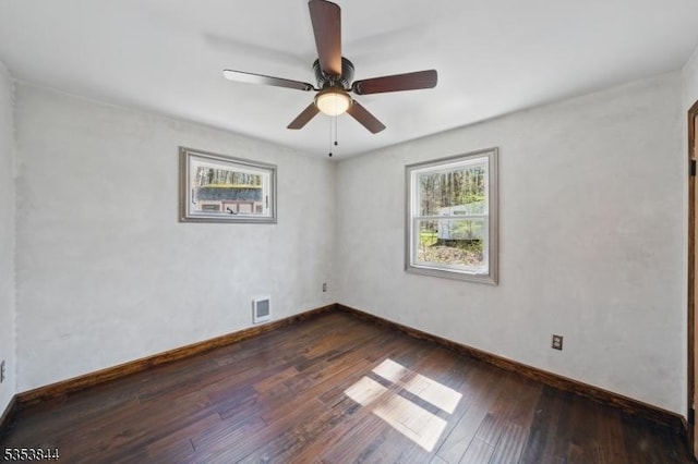 spare room featuring dark wood-style flooring, baseboards, visible vents, and a ceiling fan