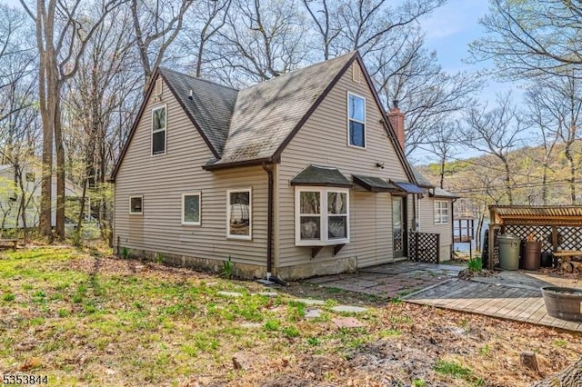 rear view of house with a wooden deck, a shingled roof, and a chimney