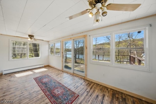 unfurnished sunroom featuring a water view, plenty of natural light, and baseboard heating