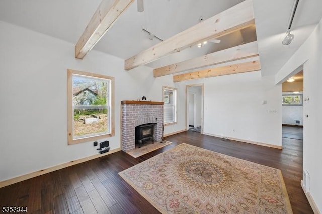 living room with a wood stove, dark wood finished floors, a healthy amount of sunlight, and beamed ceiling