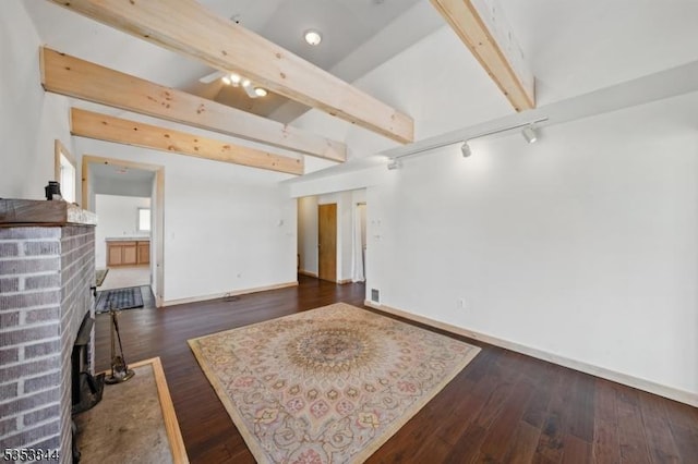 unfurnished living room featuring baseboards, rail lighting, dark wood-style floors, and visible vents
