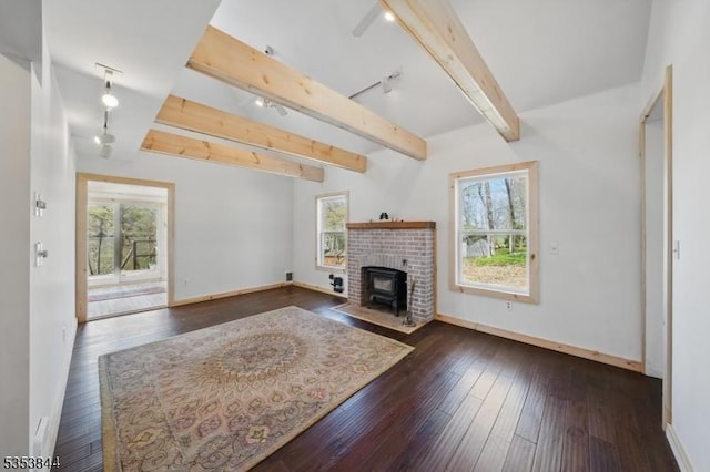 unfurnished living room with baseboards, track lighting, and a healthy amount of sunlight