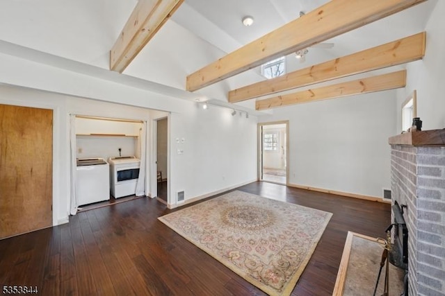 living room featuring washing machine and dryer, a brick fireplace, baseboards, lofted ceiling with beams, and dark wood-type flooring