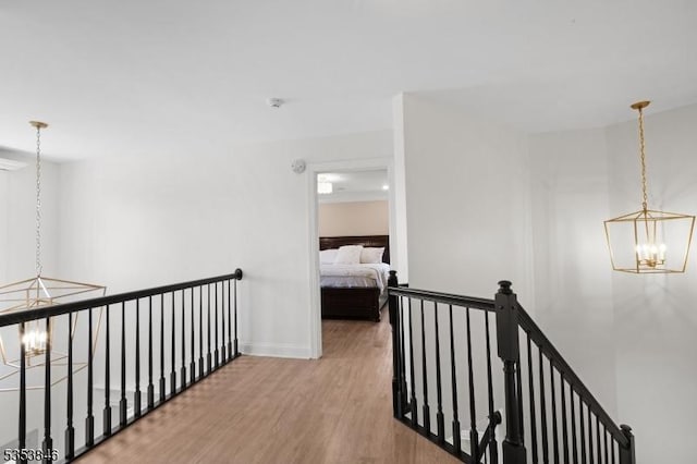 hall featuring wood finished floors, a chandelier, an upstairs landing, and baseboards