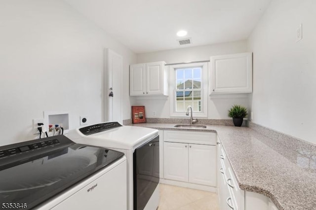 laundry area with a sink, cabinet space, visible vents, light tile patterned floors, and washing machine and dryer