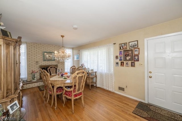 dining area with visible vents, light wood finished floors, baseboards, and a chandelier