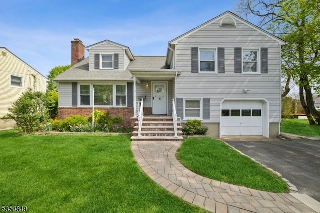 tri-level home featuring a garage, a front lawn, aphalt driveway, a chimney, and brick siding
