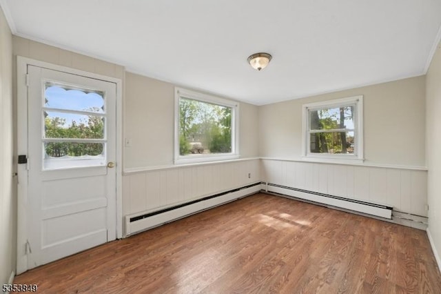 interior space featuring a baseboard heating unit, wood finished floors, and wainscoting