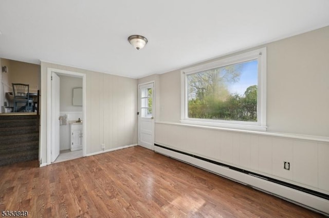 unfurnished bedroom with wood finished floors and baseboard heating