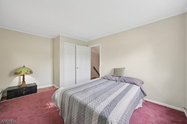 bedroom with a closet, baseboards, crown molding, and carpet flooring