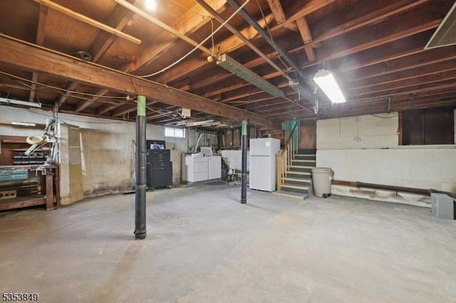 below grade area with freestanding refrigerator, separate washer and dryer, and stairway