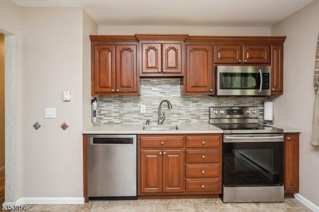 kitchen featuring light countertops, baseboards, appliances with stainless steel finishes, and a sink