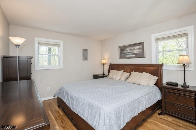 bedroom featuring baseboards, multiple windows, and wood finished floors