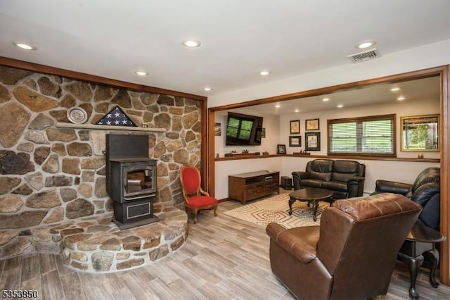 living area with a wood stove, recessed lighting, wood finished floors, and visible vents