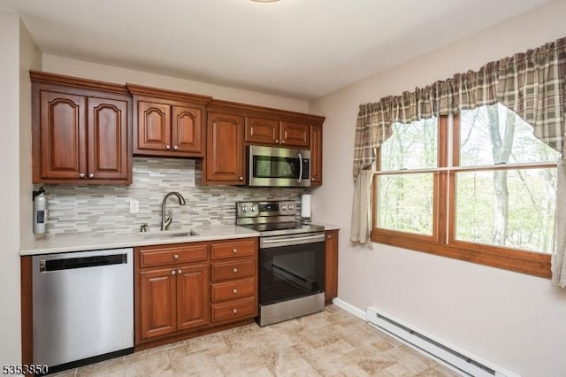 kitchen featuring decorative backsplash, light countertops, a baseboard heating unit, a sink, and stainless steel appliances