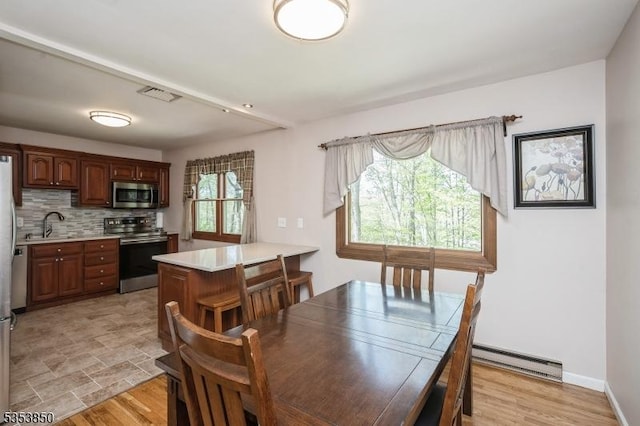 dining area with a baseboard radiator, light wood finished floors, and visible vents