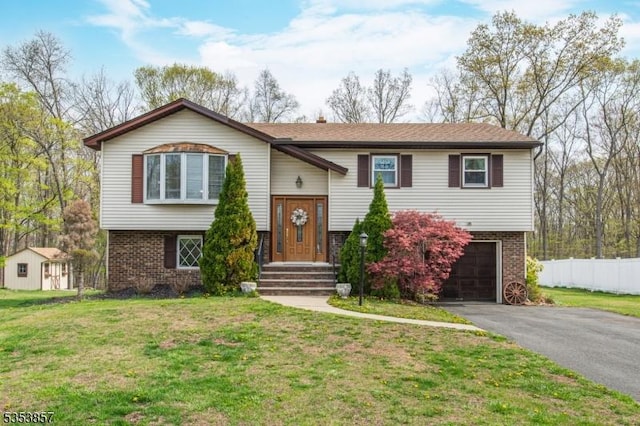 split foyer home featuring brick siding, a garage, fence, and driveway
