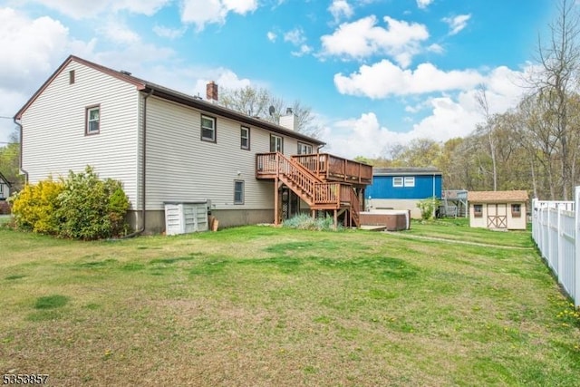 back of house featuring a deck, a chimney, a storage unit, an outbuilding, and a yard