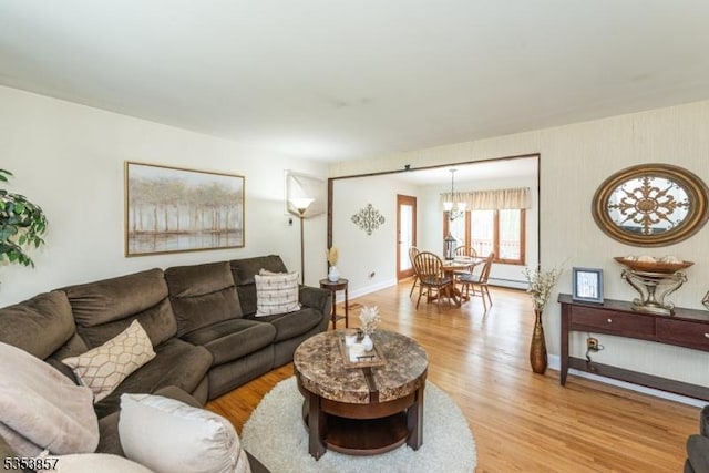 living room with baseboards, a baseboard radiator, light wood-type flooring, and a chandelier