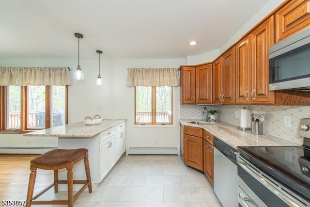 kitchen featuring appliances with stainless steel finishes, a sink, baseboard heating, a peninsula, and a baseboard radiator