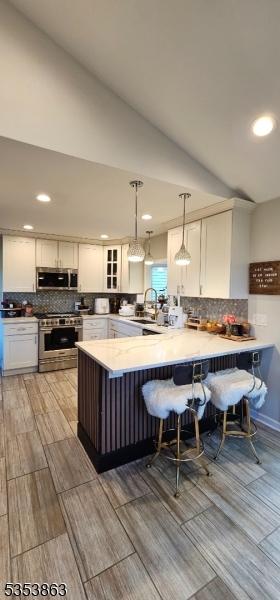 kitchen with appliances with stainless steel finishes, a peninsula, recessed lighting, decorative backsplash, and glass insert cabinets