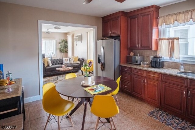 kitchen featuring ceiling fan, backsplash, appliances with stainless steel finishes, a sink, and light tile patterned flooring