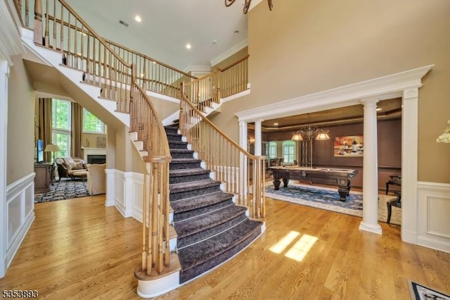 28 Arbor Rd, North Caldwell Boro, NJ 07006 - staircase featuring billiards table, wood finished floors, a decorative wall, a high ceiling, and ornate columns