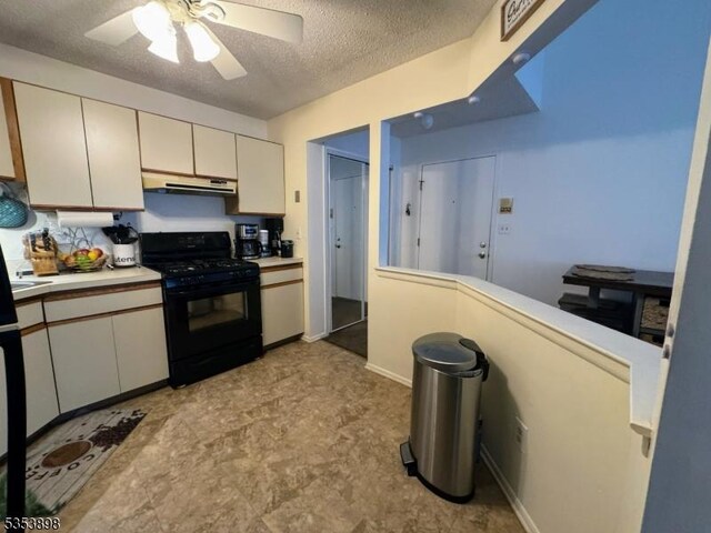kitchen featuring ceiling fan, light countertops, a textured ceiling, under cabinet range hood, and gas stove