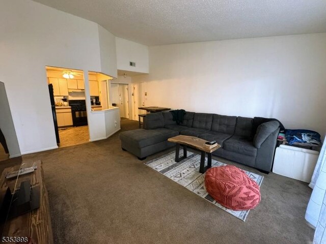 carpeted living room featuring a textured ceiling, visible vents, and high vaulted ceiling