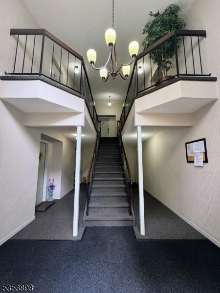 stairs featuring carpet flooring, baseboards, and a chandelier