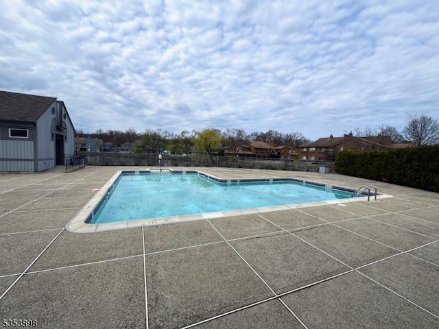 community pool with a patio and fence