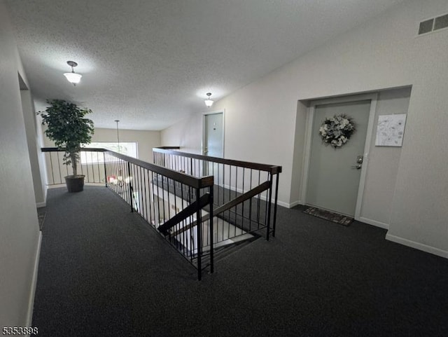 corridor with baseboards, an upstairs landing, visible vents, and dark colored carpet