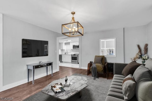 living area with baseboards, a notable chandelier, and dark wood finished floors