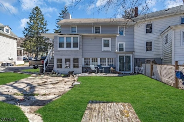 rear view of house featuring a lawn, a patio area, fence, and a chimney