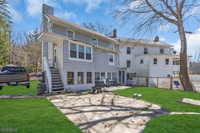 rear view of property with fence, a patio, a chimney, stairs, and a yard