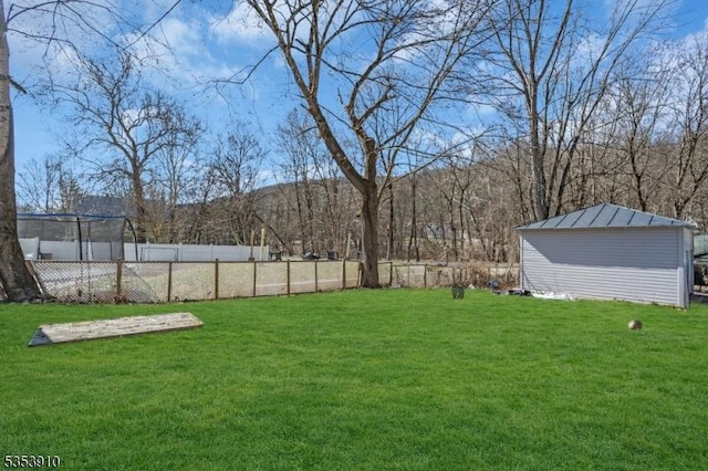 view of yard featuring an outdoor structure, fence, and a shed