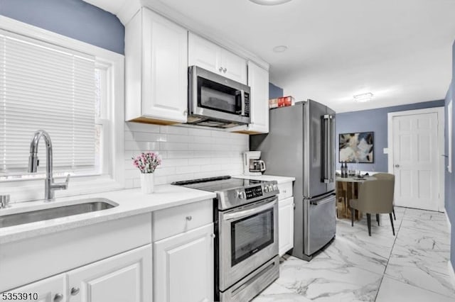 kitchen with a sink, light countertops, marble finish floor, stainless steel appliances, and white cabinetry