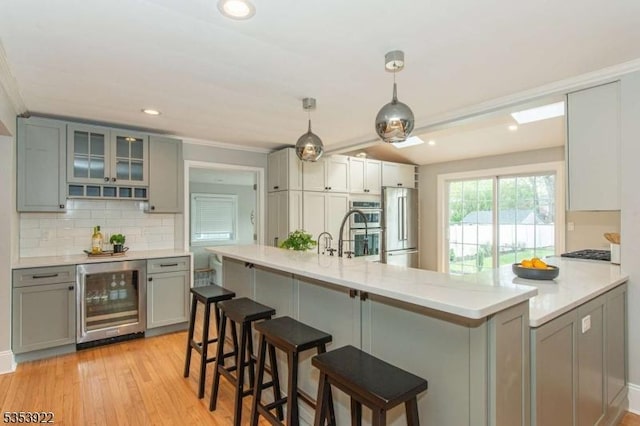kitchen with crown molding, stainless steel appliances, gray cabinetry, and wine cooler